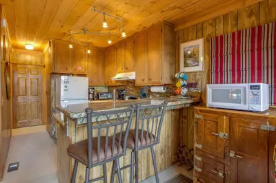 a kitchen with wooden cabinets and a counter with a microwave at Castle Rock Cabin #2 in Big Bear Lake