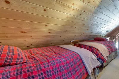 a bedroom with two beds in a wooden wall at Castle Rock Cabin #2 in Big Bear Lake