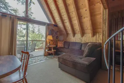 a living room with a couch and a balcony at Castle Rock Cabin #2 in Big Bear Lake