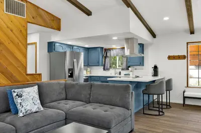a living room with a couch and a kitchen with blue cabinets at The Fox Den #2568 in Big Bear City