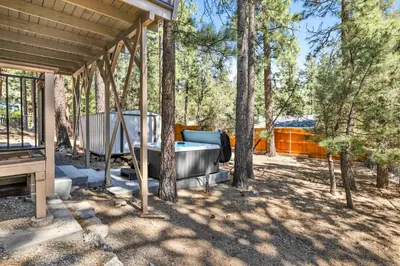 a hot tub in a backyard with trees at The Fox Den #2568 in Big Bear City