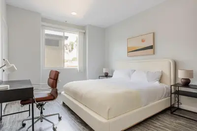a white bedroom with a bed and a desk at Blueground Sawtelle view nr Westwood Park LAX-1396 in Los Angeles