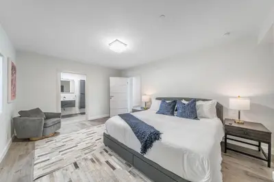 a white bedroom with a bed and a chair at Fulton Villa in Garnsey