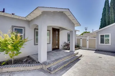 a white house with a porch and a driveway at 2 Mi to Disneyland Home with Furnished Patio! in Anaheim