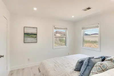 a bedroom with white walls and two windows at 7 Mi Huntington Beach Family Home with Patio! in Midway City