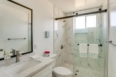 a bathroom with a shower and a toilet and a sink at 7 Mi Huntington Beach Family Home with Patio! in Midway City