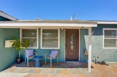 a blue house with two chairs and a door at 7 Mi Huntington Beach Family Home with Patio! in Midway City