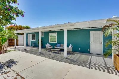 a covered porch of a blue house with a couch at 7 Mi Huntington Beach Family Home with Patio! in Midway City