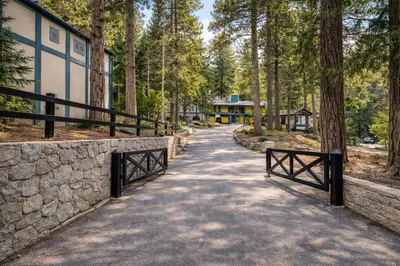 a walkway in a forest with a stone wall at Arrowhead Ranch Retreat and Conference Center in Lake Arrowhead