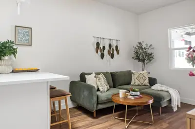 a living room with a green couch and a table at All New Apt Mins Beach, Downtown & Convention Ctr LB ADU in Long Beach