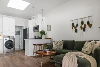 a living room with a green couch and a kitchen at All New Apt Mins Beach, Downtown & Convention Ctr LB ADU in Long Beach