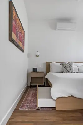 two beds in a room with white walls and wooden floors at All New Apt Mins Beach, Downtown & Convention Ctr LB ADU in Long Beach