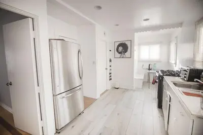 a white kitchen with a refrigerator and a wooden floor at Private Room in East Hollywood in Los Angeles