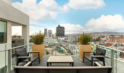 a balcony with chairs and a table and a view of a city at Mid Century With Pool GYM and Parking 10min to Cedars in Los Angeles