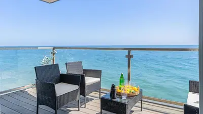 a deck with chairs and a table on the water at Beach Retreat with Oceanfront Balconies Direct Beach Access Pacific Coast Outlook by AvantStay in Malibu Beach