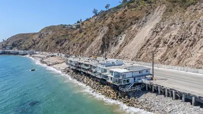 a train parked next to the water next to a mountain at Beach Retreat with Oceanfront Balconies Direct Beach Access Pacific Coast Outlook by AvantStay in Malibu Beach
