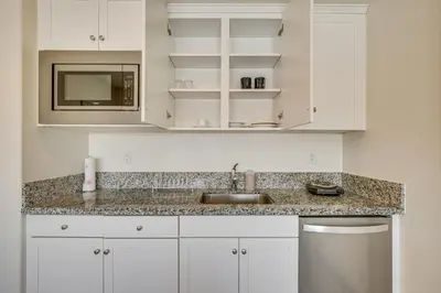 a kitchen with white cabinets and a sink and a microwave at Cozy Desert Sanctuary 9 Mi to Mojave Narrows Park! in Victorville