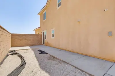 a building with a sidewalk next to a brick wall at Cozy Desert Sanctuary 9 Mi to Mojave Narrows Park! in Victorville