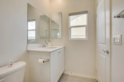 a white bathroom with a sink and a mirror at Cozy Desert Sanctuary 9 Mi to Mojave Narrows Park! in Victorville