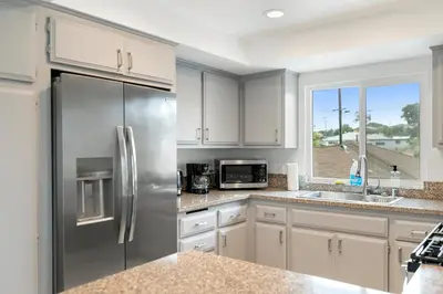 a kitchen with white cabinets and a stainless steel refrigerator at Bay Breeze Hideaway in Lawndale