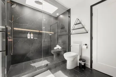 a bathroom with a toilet and a glass shower at Hillside Modern Retreat with pool BBQ and MORE in Los Angeles