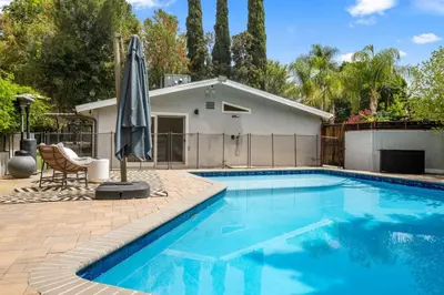 a swimming pool with an umbrella next to a house at Hillside Modern Retreat with pool BBQ and MORE in Los Angeles