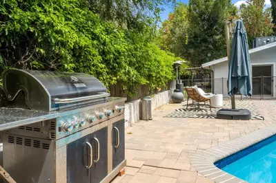 a outdoor kitchen with a grill and a swimming pool at Hillside Modern Retreat with pool BBQ and MORE in Los Angeles
