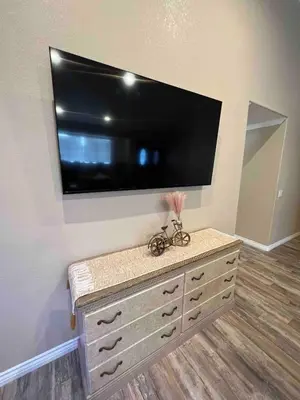 a large flat screen tv on a wall with a dresser at Beautiful and cozy! in Palmdale