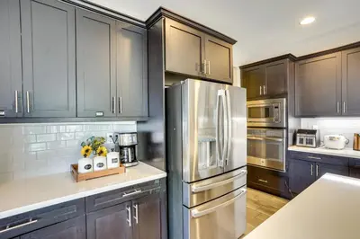 a kitchen with black cabinets and a stainless steel refrigerator at 3 Mi to Disneyland Home with Hot Tub and Game Room in Anaheim
