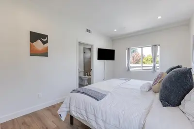 a white bedroom with a bed and a television at LA Haven Spacious Townhome in Sherman Oaks Community Hospital Heliport