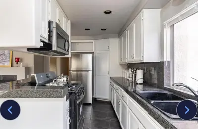 a kitchen with white cabinets and a sink at Desert View in Victorville