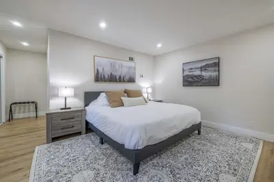 a white bedroom with a bed and a nightstand with two lamps at Moonlight Ridge Jacuzzi, Gated, EV Charge, Cent AC in Big Bear City Airport