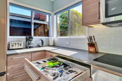 a kitchen with an open dishwasher in a sink at Modern Pool house with hot tub and relaxing backyard in Long Beach