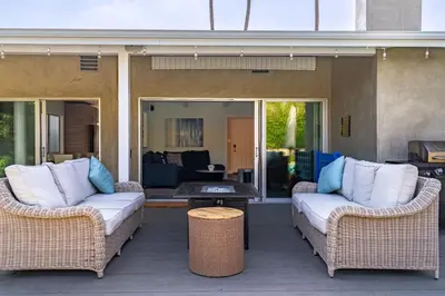 two wicker chairs and a table on a patio at Modern Pool house with hot tub and relaxing backyard in Long Beach