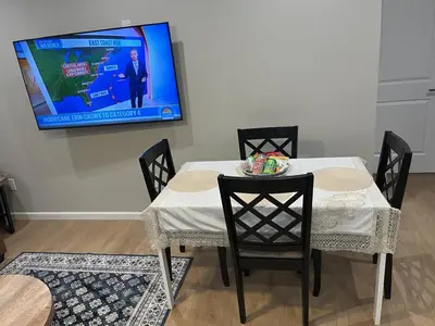 a table with chairs and a tv on a wall at Guest House in Torrance