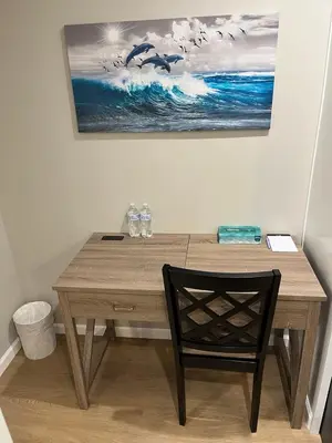 a wooden desk with a chair and a painting on the wall at Guest House in Torrance