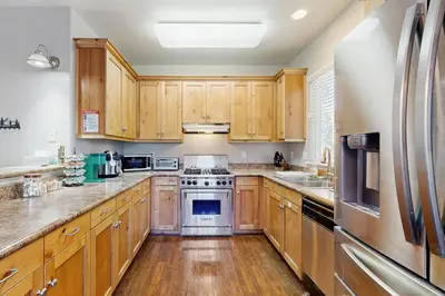 a kitchen with wooden cabinets and stainless steel appliances at 7 Mi to Snow Valley Mountain Resort Quiet Cabin in Running Springs