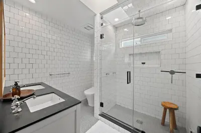 a white tiled bathroom with a sink and a shower at New Listing Midcity West Villa by Colby & Conrad in Los Angeles