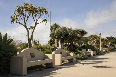 a row of stone benches in a park with trees at Waterfront 104 in Oxnard