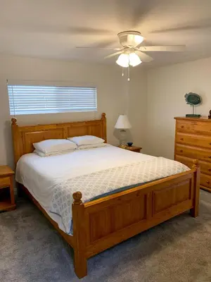a bedroom with a wooden bed and a ceiling fan at Ocean Blue in Oxnard