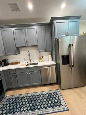 a kitchen with gray cabinets and a stainless steel refrigerator at House in Torrance