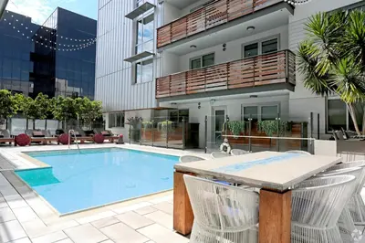 a swimming pool with two chairs and a table in front of a building at The Amber Serene Peaceful Retreat Pool Gym And Jacuzzi in Los Angeles