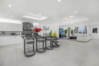 a kitchen and living room with white cabinets and bar stools at Rancho Haven in Los Angeles