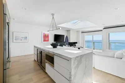 a white kitchen with a large island with a view of the ocean at Playa Del Sol by Stay Awhile Villas in Malibu Beach