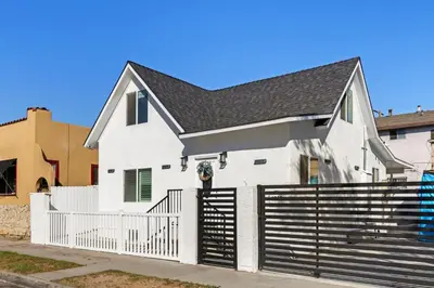 a white house with a black roof and a fence at #Marbella Lane - Cityside Haven with Touch of Charm in Compton