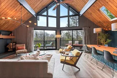 a living room with wooden ceilings and a large window at BlackOak Hideaway in Lake Arrowhead