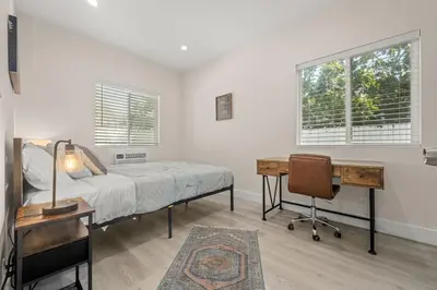 a bedroom with a bed and a desk and windows at Stay on Hart in Los Angeles