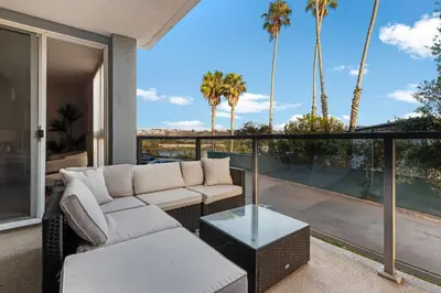 a living room with a couch and a balcony with palm trees at Azure Marina Luxe - Waterfront with Sunset Views in Los Angeles