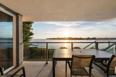 a table and chairs on a balcony with a view of the water at Azure Marina Luxe - Waterfront with Sunset Views in Los Angeles