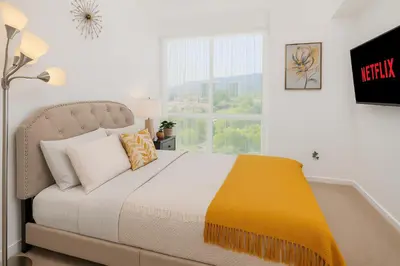 a bedroom with a bed with a yellow blanket and a window at High stay, new furniture apartment in Glendale